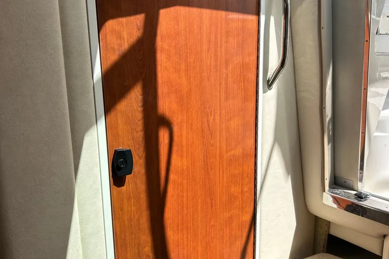 Slide: The Image of Wooden cabin door on a 2007 Sea Ray 240 Sundancer boat, with sunlight and shadows. - 22