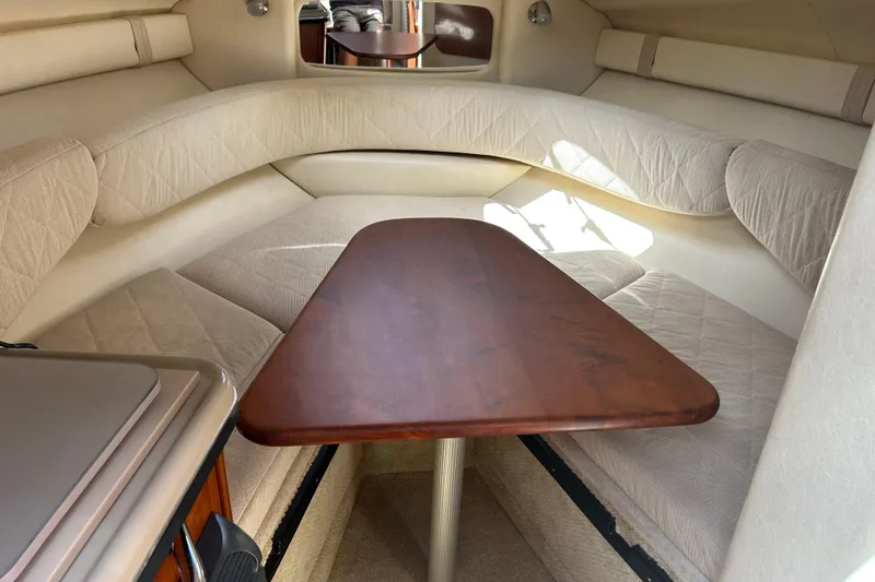 Slide: The Image of 2007 Sea Ray 240 Sundancer cabin interior with cushioned seating and wooden table. - 25