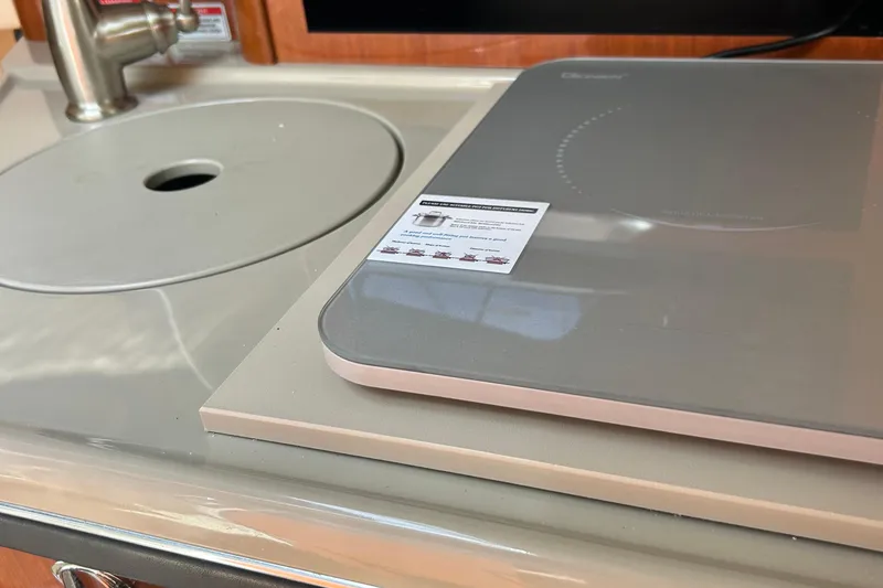 Slide: The Image of 2007 Sea Ray 240 Sundancer kitchen area with sink and induction cooktop. - 29