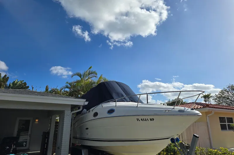 Slide: The Image of 2007 Sea Ray 240 Sundancer boat parked beside a house under a clear blue sky. - 55