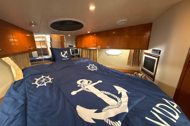 Slide: The Image of Luxurious 2005 Carver 36 Sedan cabin with nautical-themed bedding and elegant wood cabinetry. - 19
