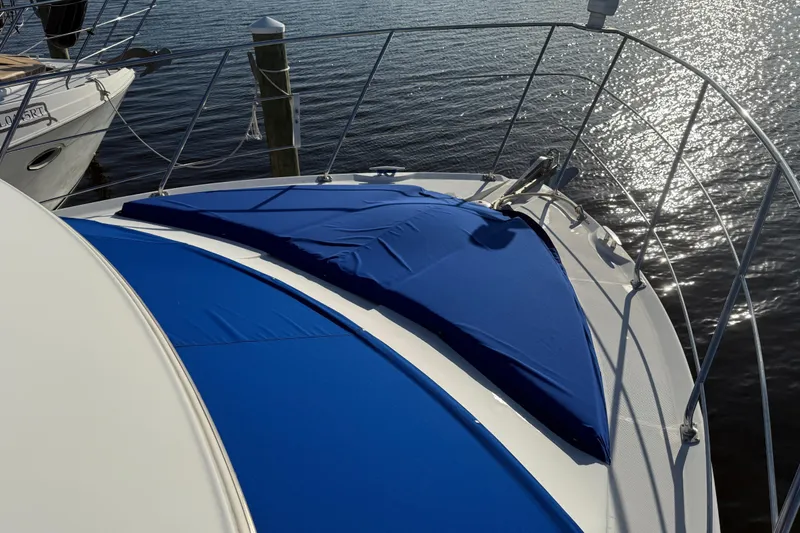 Slide: The Image of 2005 Carver 36 Sedan yacht with blue sun pads on deck, docked by shimmering water. - 26