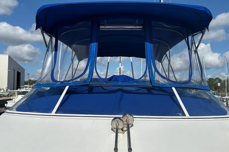 Slide: The Image of 2005 Carver 36 Sedan with blue canopy, docked under a cloudy sky. - 42