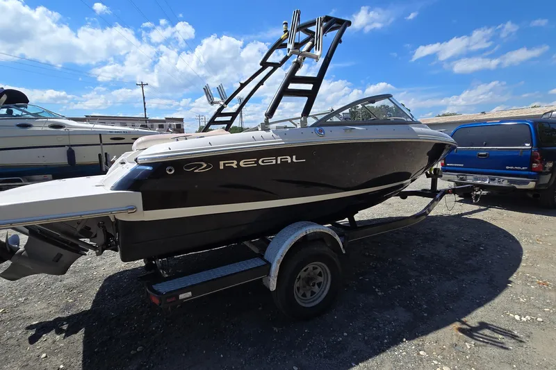 Slide: The Image of 2015 Regal 1900 Bowrider boat on trailer under a sunny sky. - 1