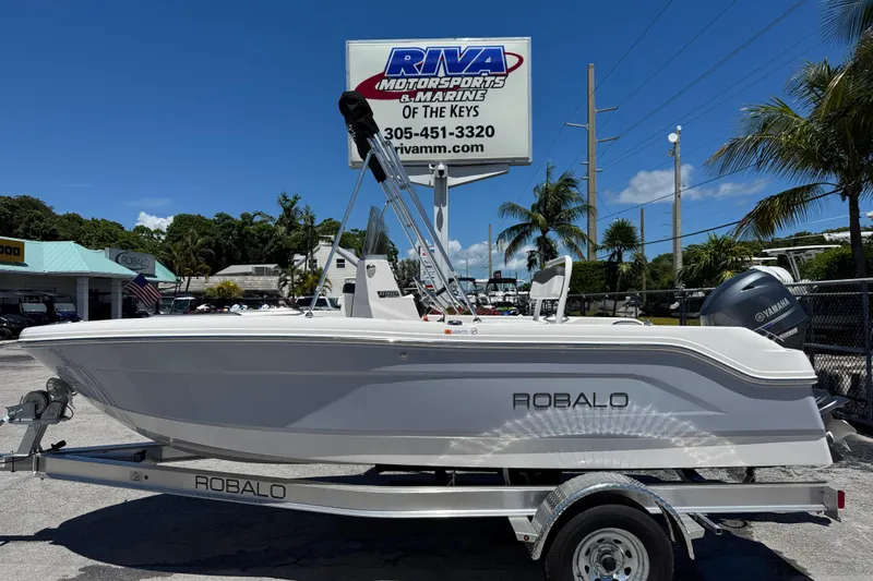 The Image of 2025 Robalo R160 Center Console boat on trailer at dealership, sunny day. - 0