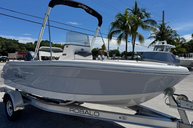 Slide: The Image of 2025 Robalo R160 Center Console boat on trailer, parked outdoors under clear sky. - 2