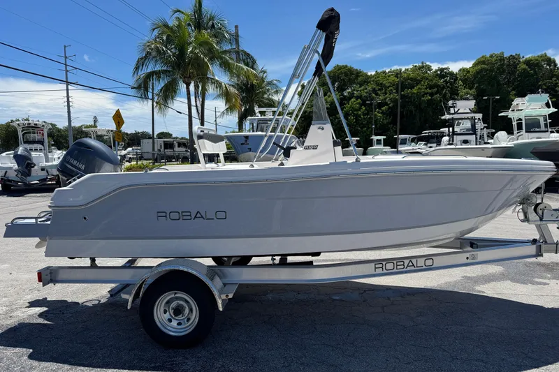 Slide: The Image of 2025 Robalo R160 Center Console boat on trailer, parked outdoors under palm trees. - 3