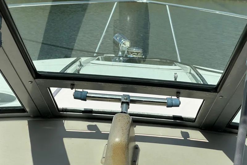 Slide: The Image of 2005 Sea Ray 300 Sundancer helm view with windshield and water in background. - 24