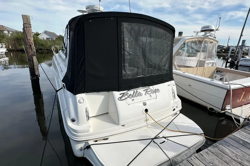Slide: The Image of 2005 Sea Ray 300 Sundancer docked, rear view with black canopy and "Bella Rose" name. - 3