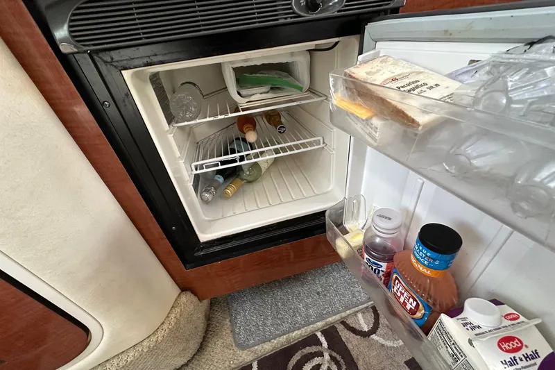 Slide: The Image of Mini fridge inside 2005 Sea Ray 300 Sundancer, stocked with beverages and food items. - 30