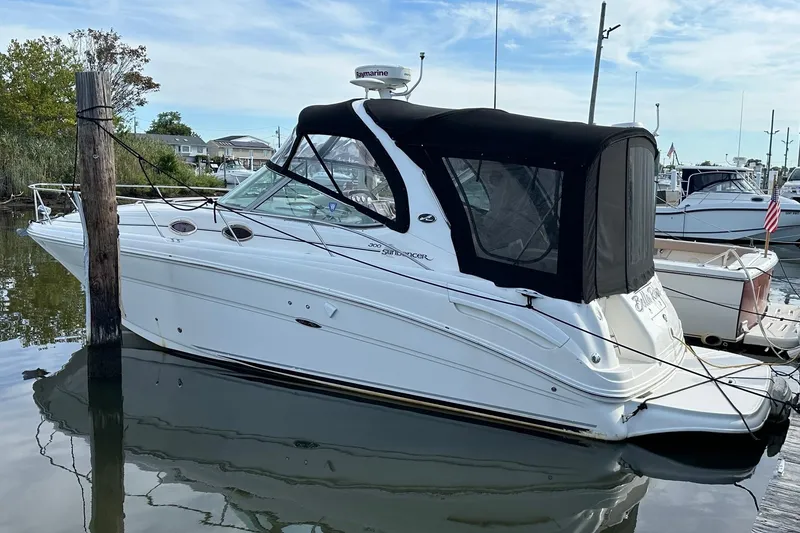 Slide: The Image of 2005 Sea Ray 300 Sundancer boat docked in a marina, featuring a black canopy. - 7