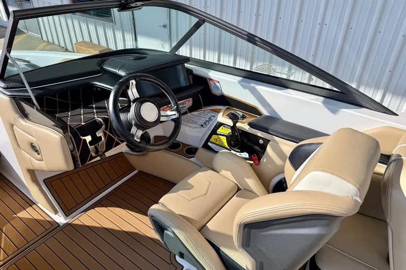 Slide: The Image of 2020 Nautique Super Air Nautique 230 boat interior with tan seats and sleek dashboard. - 14