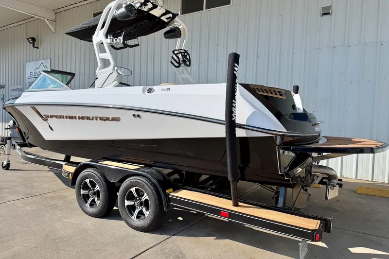 Slide: The Image of 2020 Nautique Super Air Nautique 230 boat on trailer, parked outside a building. - 3