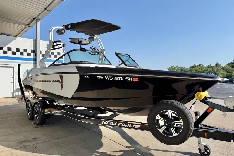 Slide: The Image of 2020 Nautique Super Air Nautique 230 boat on trailer, black exterior, parked outdoors. - 9