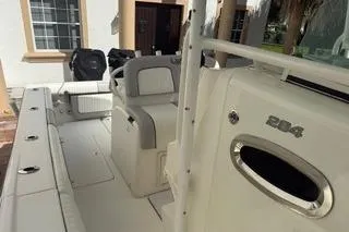 Slide: The Image of 2015 Mako 284 Center Console boat, white interior, docked near a building. - 10