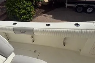 Slide: The Image of 2015 Mako 284 Center Console boat interior with cushioned seating and rod holders. - 15