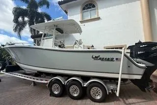 Slide: The Image of 2015 Mako 284 Center Console boat on trailer, parked near a house. - 20