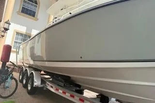 Slide: The Image of 2015 Mako 284 Center Console boat on trailer near house. - 23