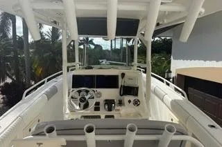 Slide: The Image of 2015 Mako 284 Center Console boat with steering wheel and control panel, surrounded by tropical scenery. - 4