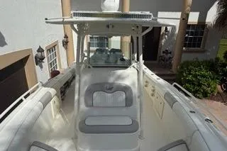 Slide: The Image of 2015 Mako 284 Center Console boat with white seating and T-top, docked near a house. - 8