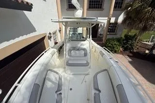 Slide: The Image of 2015 Mako 284 Center Console boat docked near a house, showcasing spacious seating. - 9