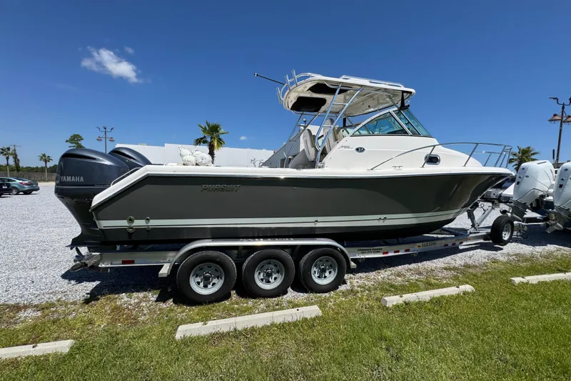 Slide: The Image of 2015 Pursuit OS 285 Offshore boat on trailer, parked outdoors under clear blue sky. - 11