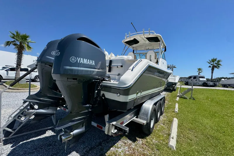 Slide: The Image of 2015 Pursuit OS 285 Offshore boat with Yamaha engines on a trailer, parked outdoors. - 13