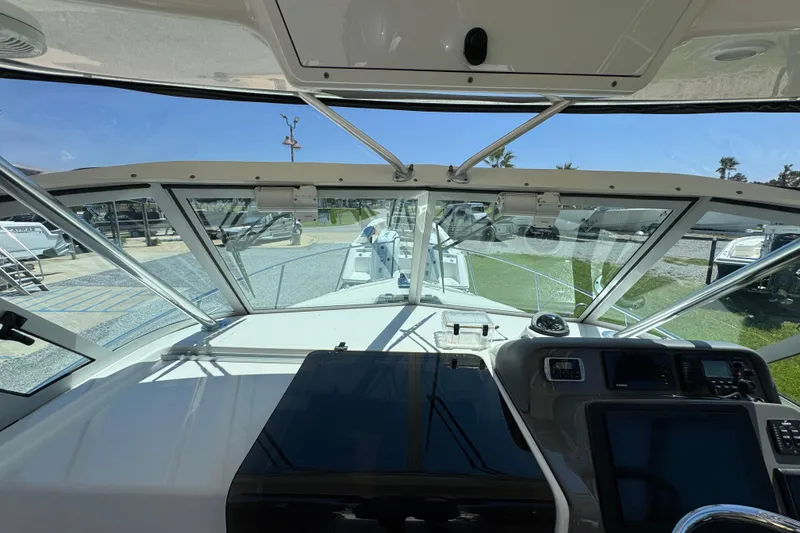 Slide: The Image of 2015 Pursuit OS 285 Offshore boat interior with dashboard and windshield view. - 18