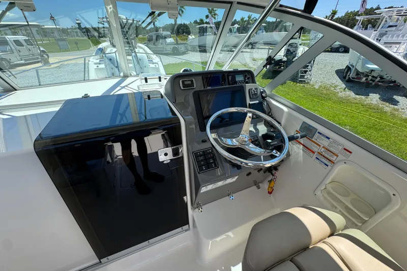Slide: The Image of 2015 Pursuit OS 285 Offshore boat helm with steering wheel and navigation controls. - 19