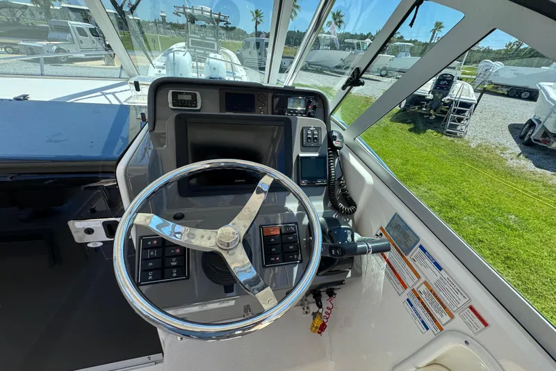 Slide: The Image of 2015 Pursuit OS 285 Offshore boat helm with steering wheel and control panel. - 20