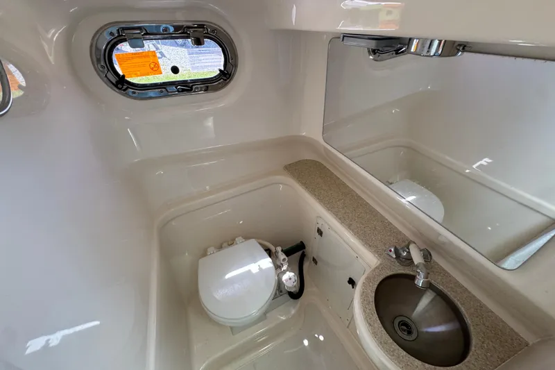 Slide: The Image of 2015 Pursuit OS 285 Offshore boat bathroom with sink, toilet, and porthole window. - 31