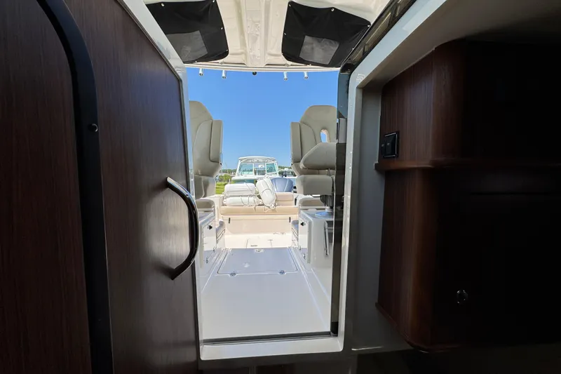 Slide: The Image of Interior view of 2015 Pursuit OS 285 Offshore boat, showcasing seating and cabin entrance. - 32