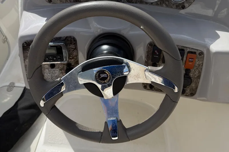 Slide: The Image of Steering wheel of 2014 Stingray 208 LR boat, featuring chrome accents and dashboard controls. - 22