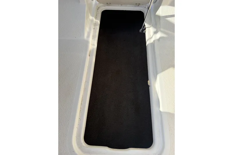 Slide: The Image of 2014 Stingray 208 LR boat storage compartment with black carpet interior. - 29
