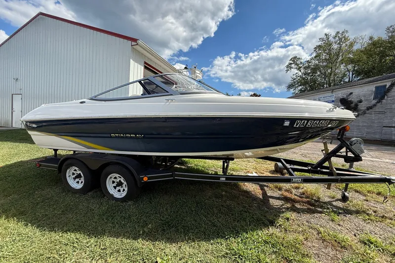 Slide: The Image of 2014 Stingray 208 LR boat on trailer, parked outdoors under a blue sky. - 3