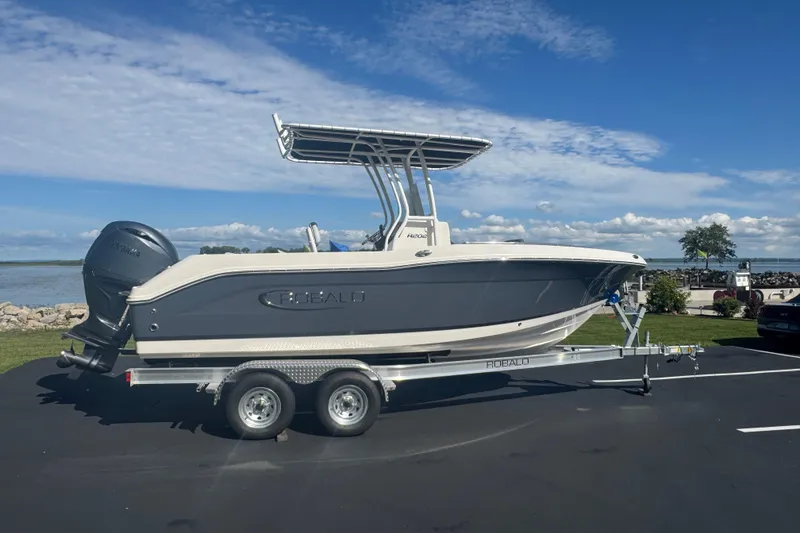 Slide: The Image of 2026 Robalo R202 Explorer boat on trailer, parked near a scenic waterfront. - 1