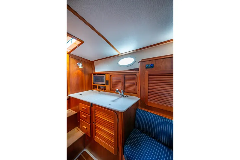 Slide: The Image of 2017 Hinckley Picnic Boat 37 MKIII interior with wooden cabinetry and compact kitchen area. - 18
