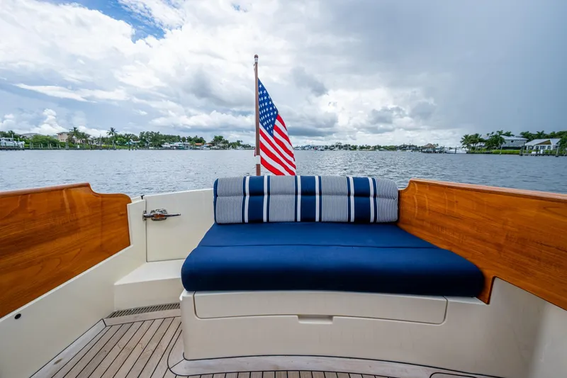 Slide: The Image of 2017 Hinckley Picnic Boat 37 MKIII with American flag, blue seating, and scenic water view. - 5