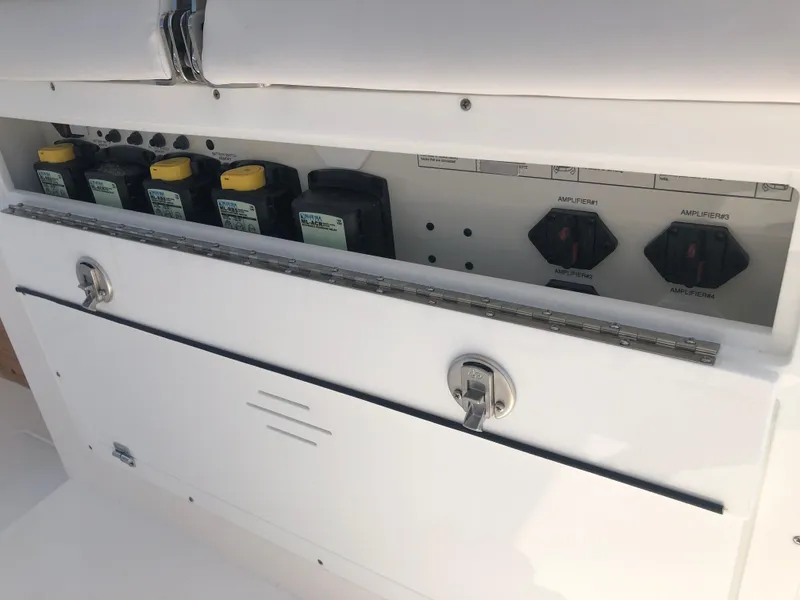 Slide: The Image of Storage compartment on 2025 Caymas 30 CT boat with battery switches and oil containers. - 16