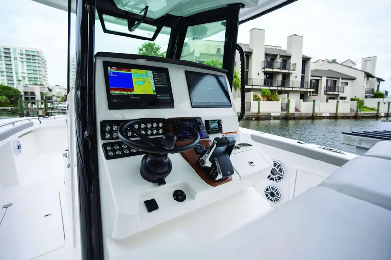 Slide: The Image of 2026 Caymas 30 CT boat dashboard with advanced navigation system, docked near waterfront homes. - 46