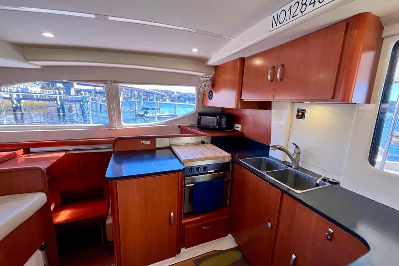 Slide: The Image of Interior of 2012 Leopard 47 PC Owners' Version yacht kitchen with wood cabinetry and dual sinks. - 11