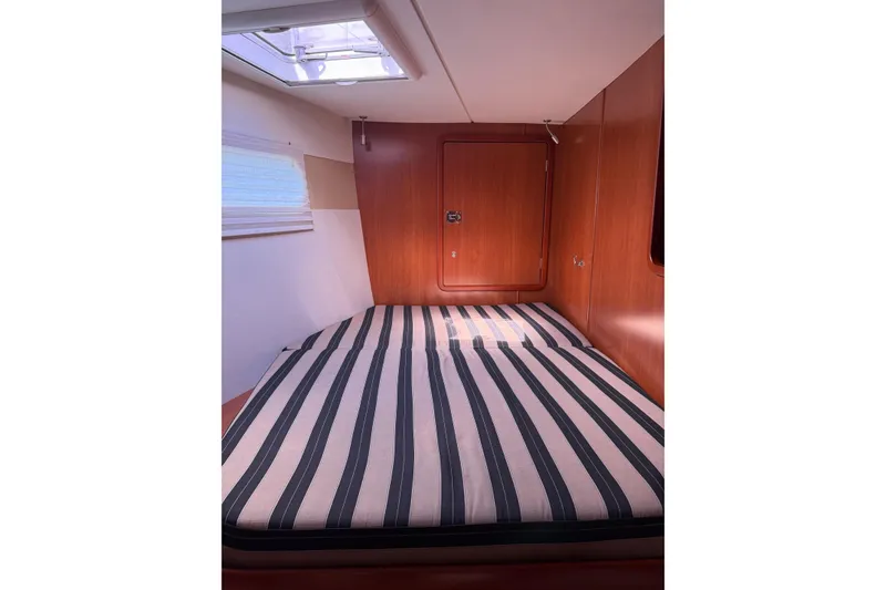 Slide: The Image of Cabin interior of 2012 Leopard 47 PC Owners' Version with striped bedding and wooden paneling. - 29