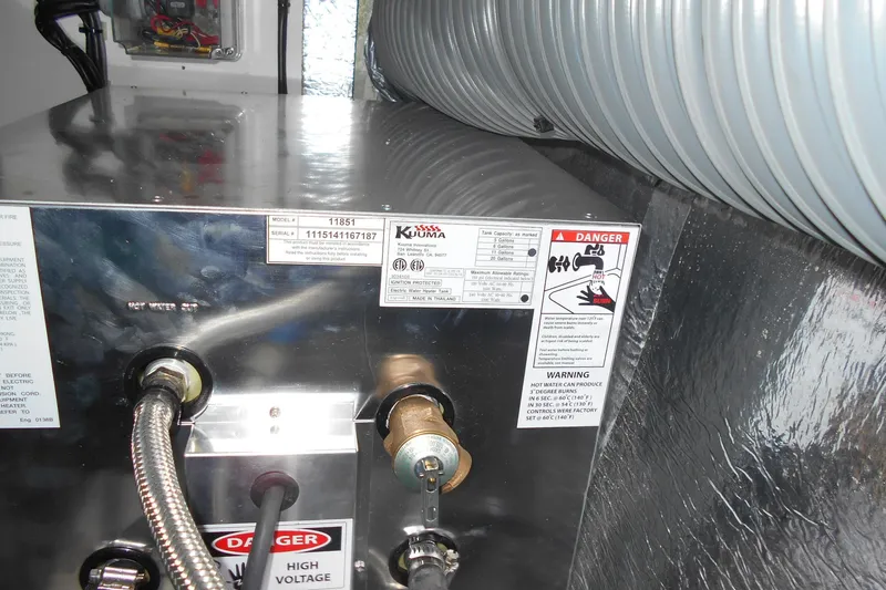 Slide: The Image of Close-up of a Kuuma water heater with warning labels and connections, Leopard 47 PC 2012 model. - 49