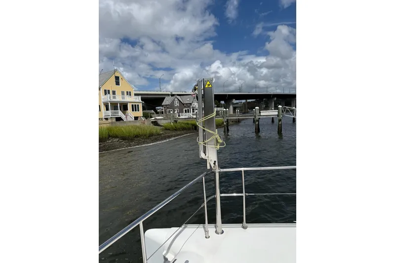 Slide: The Image of Leopard 47 PC Owners' Version 2012 boat near waterfront homes and bridge under cloudy sky. - 58