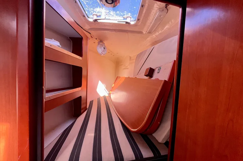 Slide: The Image of Interior cabin of 2012 Leopard 47 PC Owners' Version with striped bedding and wooden shelves. - 64