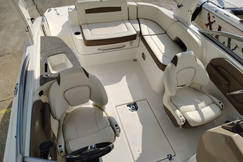 Slide: The Image of 2017 Chaparral 244 Sunesta boat interior with beige seating and steering wheel. - 23
