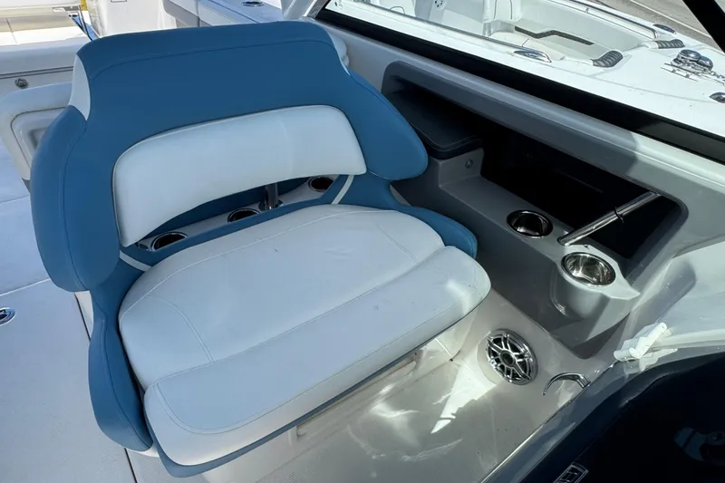 Slide: The Image of 2026 Robalo R317 Dual Console boat interior with blue and white seating, cup holders, and storage. - 15