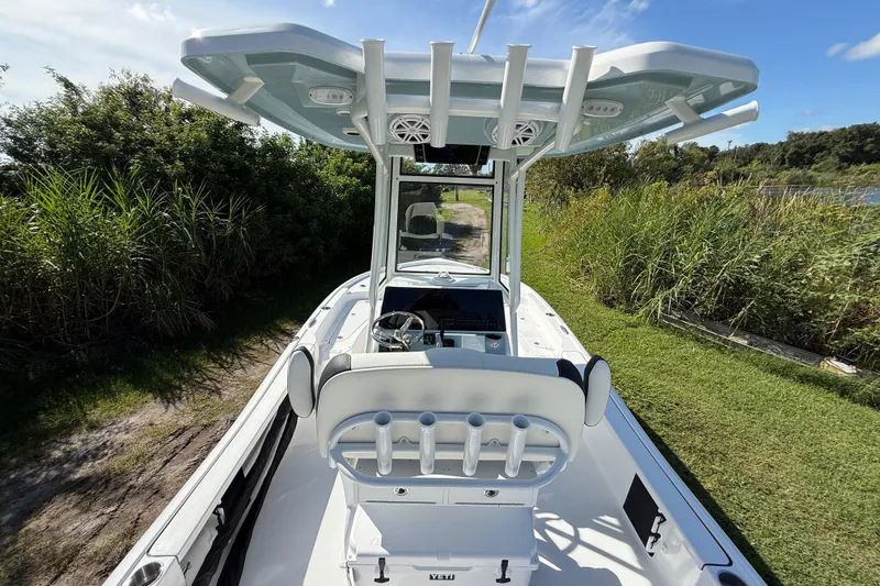 Slide: The Image of 2026 Tidewater 2210 Carolina Bay boat with T-top, docked near lush greenery. - 13