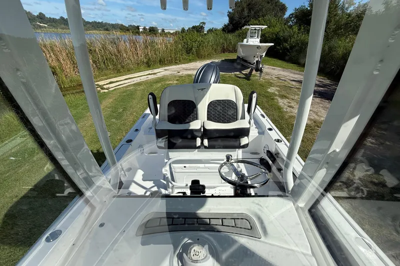 Slide: The Image of 2026 Tidewater 2210 Carolina Bay boat interior with steering wheel and seating, near a lake. - 21