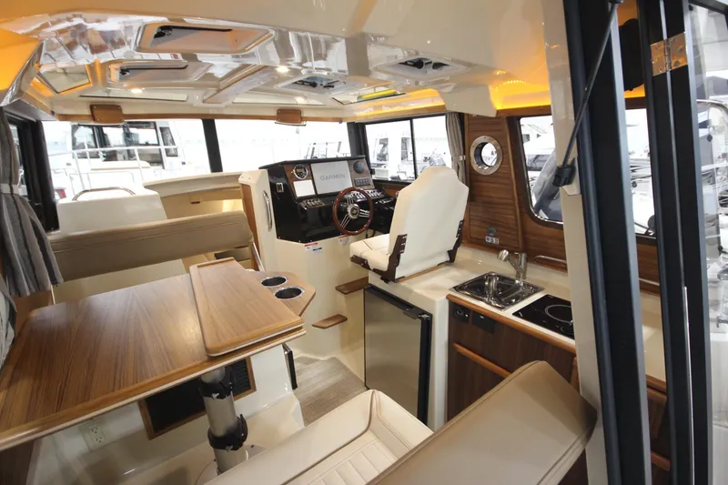 Slide: The Image of Interior of 2026 Ranger Tugs R-25 boat with modern helm, kitchenette, and seating area. - 18